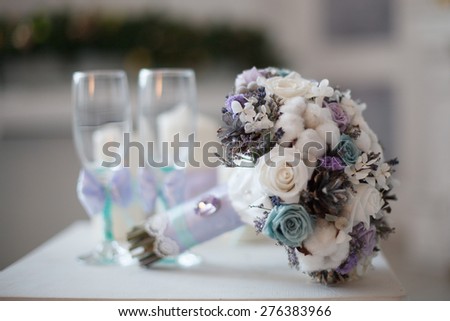Winter wedding bouquet. Wedding bouquet of flowers lying on a chair near two wedding glasses.