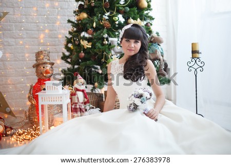 Christmas and bride. Pretty bride is sitting near the Christmas tree.