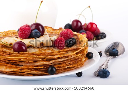 Pancakes with berries on a white background