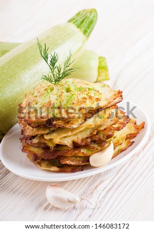 Green zucchini pancakes on a wooden board old