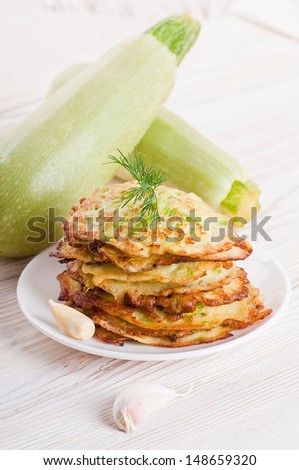 Green zucchini pancakes on a wooden board old