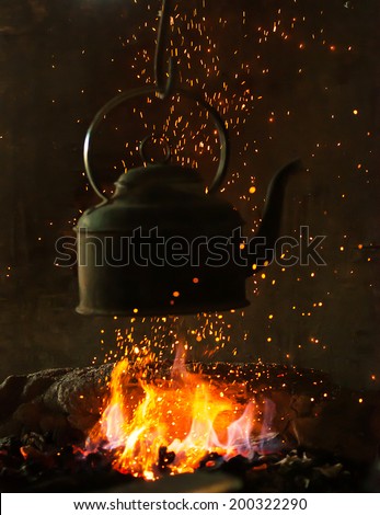 Old iron kettle on the fire, sparks fire