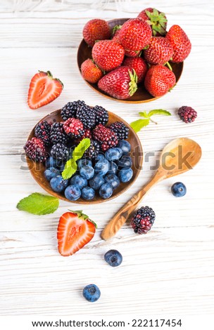 A bunch of wild berries and mint on a wooden board