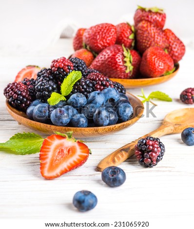 Ã?Â�?unch of wild berries and mint on a wooden board