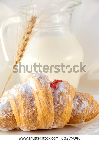 Croissant with jam and a milk jug, a light morning meal