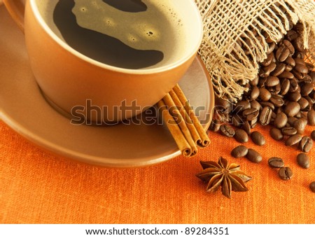 Cup of coffee and bag of grains in bulk on a orange background