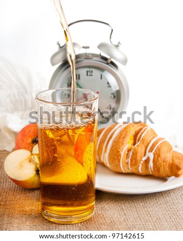 Juice, croissant and apple for a breakfast, an alarm clock