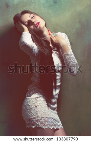 Young passionate woman in lace dress lean against the grunge wall