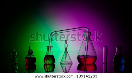 Laboratory glassware with liquids on dark colorful background