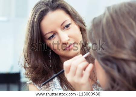 Make-up artist at work, close up, selective focus, there is a model out of focus on foreground