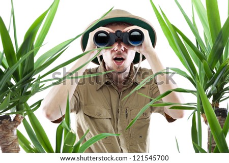 Young man looking through binoculars with an amazed expression, palm trees on foreground out of focus, isolated on white