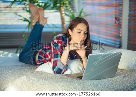 Young woman lying on the sofa and surfing the net