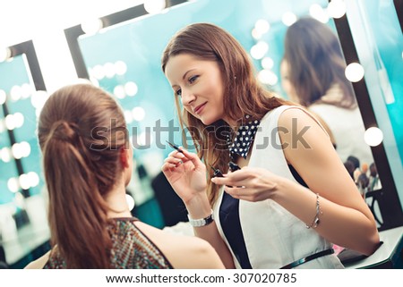 Make-up artist and model at work in front of mirror
