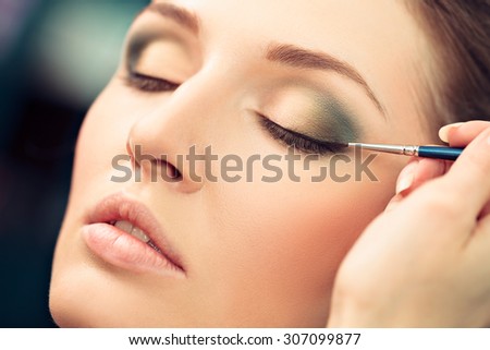 Make-up artist applying liquid eyeliner on model\'s eyes, close up