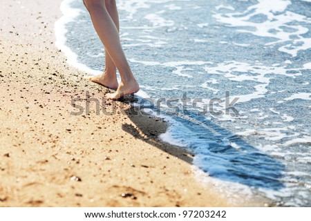 Walking barefoot along the surf on the sand beach