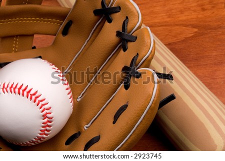 Baseball bat, ball and glove close-up on a wood table