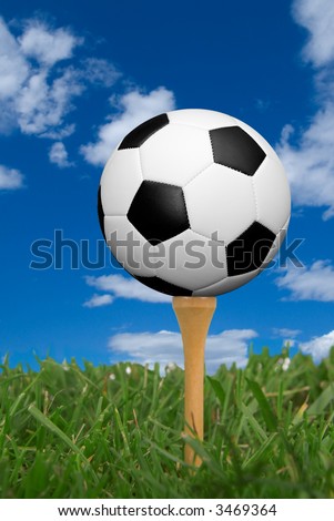 Soccer ball on golf tee from the ground level with grass and cloudy sky