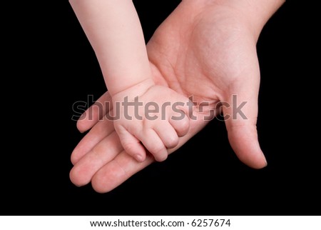 Mother holding baby\'s hand in her own isolated over black