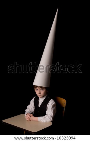 stock-photo-sad-young-boy-in-a-dunce-cap-at-a-school-desk-over-a-black-background-10323094.jpg