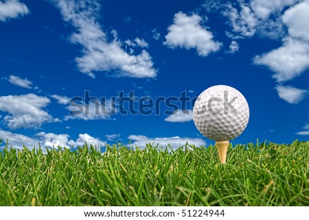 Golf ball close-up from the ground level with grass and cloudy sky