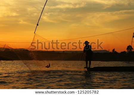 Silhouette picture of fisherman using the square dip net for fishing in twilight timing.