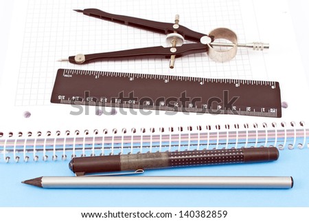 Wooden pencil, pen, drawing compass and ruler on spiral notebook