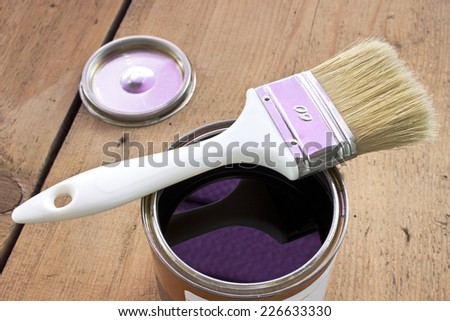 Paint brush and varnish can on wooden background