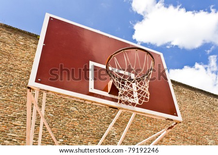 Red basketball board over brick wall and blue sky