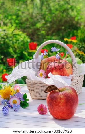 stock photo : Red apples, flowers and basket on white garden table