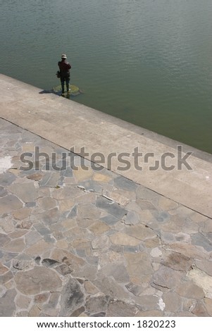 Metal statue of a man fishing in lake
