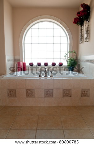 Private whirlpool bath below an arched, glass block window.