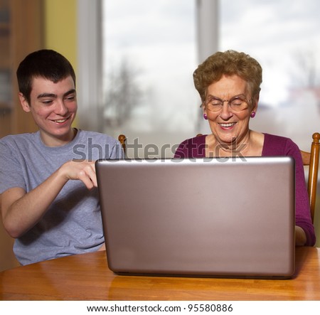 teen boy trying to teach grandmother to use a laptop