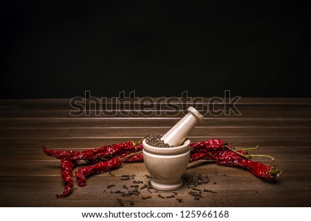 marble mortar with spices black pepper, carnation and red hot pepper on a wooden table