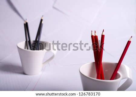 black and red pencils stand in two white cups