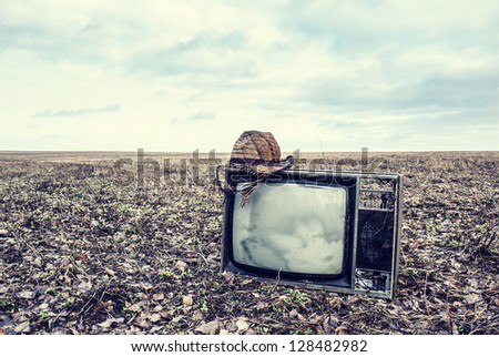 old broken TV with hat is an autumn field