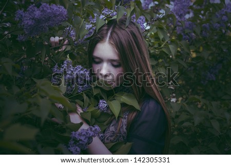 beauty girl in fashion style smells lilac flowers outdoors