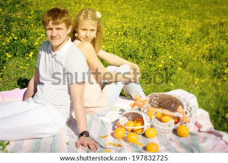 happy couple and picnic with oranges outdoors