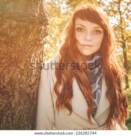 beautiful woman with freckle and red long hair in autumn park