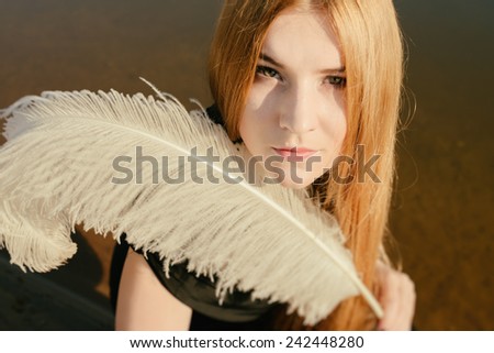 unusual gothic girl with long red hair and white feather