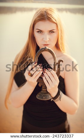 unusual gothic girl with long red hair and old mirror