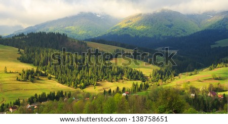 Spring morning rural landscape in the Carpathian mountains. Low clouds are on the tops of mountains.