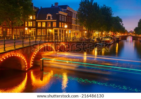 Night city view of Amsterdam canal, bridge and luminous track from the boat, Holland, Netherlands.