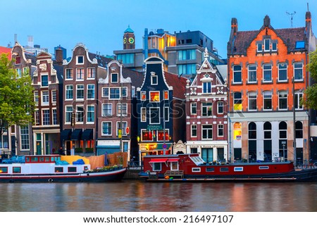 Amsterdam, Netherlands - July 30, 2014: Night city view of Amsterdam canal, typical dutch houses and boats, Holland. Canal ring area placed on the UNESCO World Heritage List.