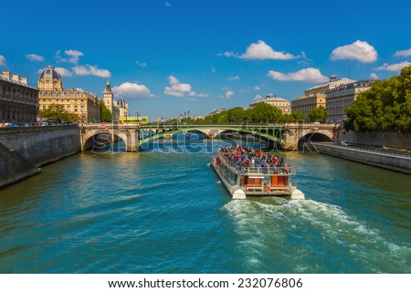 Tourist boat near Conciergerie and bridge Pont Notre-Dame over river Seine in Paris, France