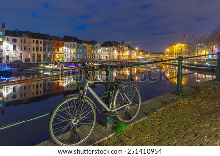 Embankment of the river Leie with bike and reflections colored houses in Ghent town at night, Belgium