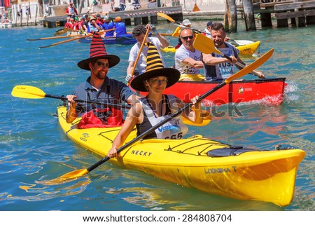 Venice, Veneto, Italy - May 24, 2015: Man and woman oarsmen in colorful hats in boat race along the Cannaregio Canal in the Venice Vogalonga regatta. More than 1,500 boats take part in the annual