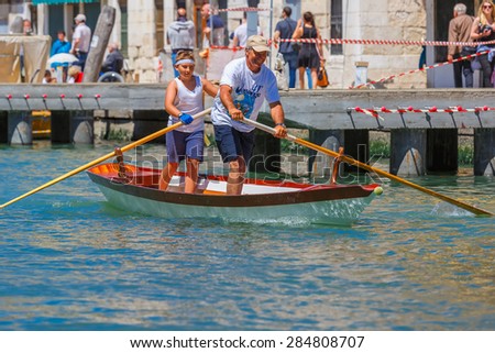 Venice, Veneto, Italy - May 24, 2015: Boy and man oarsmen, in boat race along the Cannaregio Canal in the Venice Vogalonga regatta. More than 1,500 boats take part in the annual historic regatta