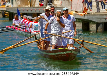 Venice, Veneto, Italy - May 24, 2015: Men oarsmen in  boat race along the Cannaregio Canal in the Venice Vogalonga regatta. More than 1,500 boats take part in the annual historic regatta. Selective