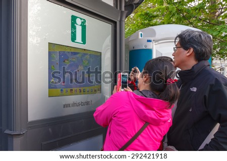 Vilnius, Lithuania - May 1, 2014: Asian tourists exploring information for travelers on the interactive board in the street of Vilnius