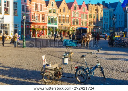 Bruges, Belgium - December 28, 2014: Street artist paints a picture of a Horse carriage waiting tourists on Grote Markt square of Brugge Christmas. Bruges is UNESCO world heritage listed for its